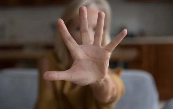 Foto de una persona mayor que con una mano delante de la cara dice basta