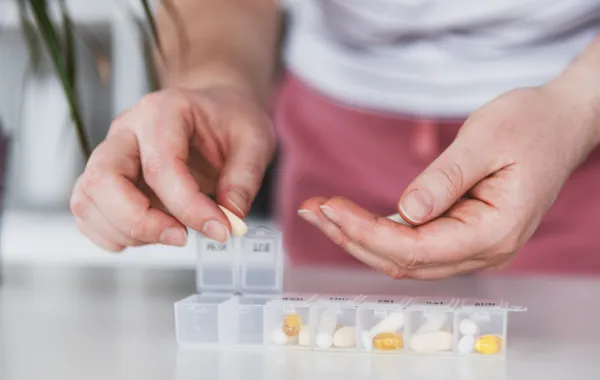 Foto de una persona colocando varias pastillas de distintos medicamentos