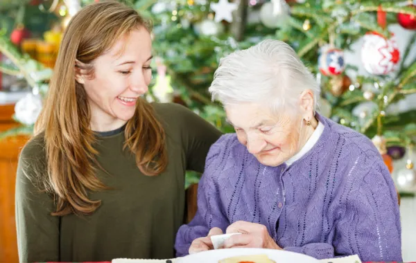 Foto de una señora mayor con una señora joven delante de un árbol de Navidad