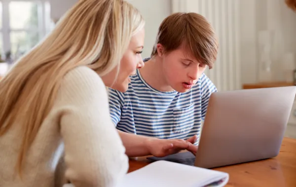 Foto de una madre con su hijo con discapacidad escribiendo en un ordenador