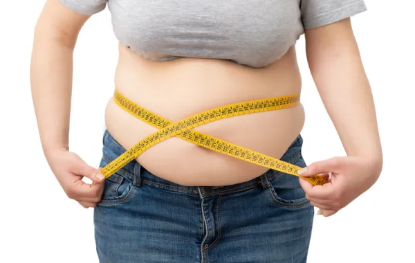 Foto de una persona obesa midiendo la tripa con una cinta metrica