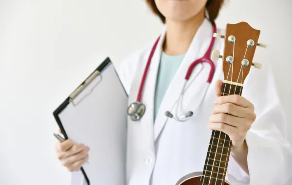 Foto de una doctora que sostiene en una mano una guitarrar