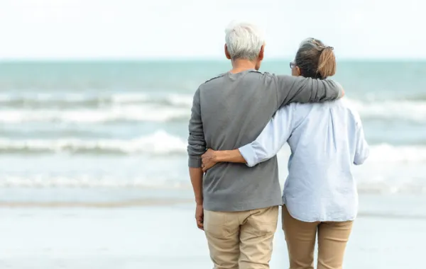 Foto de una pareja de personas adultas en la playa mirando el mar