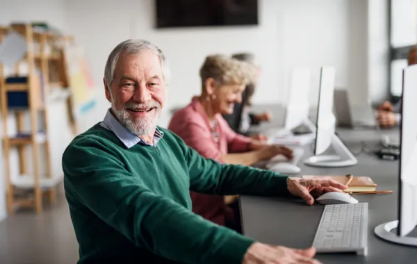 Foto de varias personas mayores escribiendo delatante de un ordenador