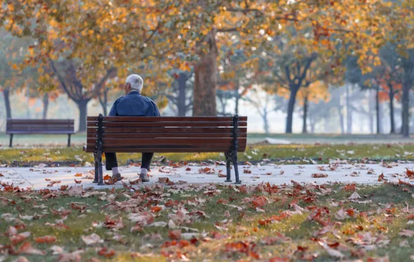 Foto de una persona mayor sentada en un banco en un parque