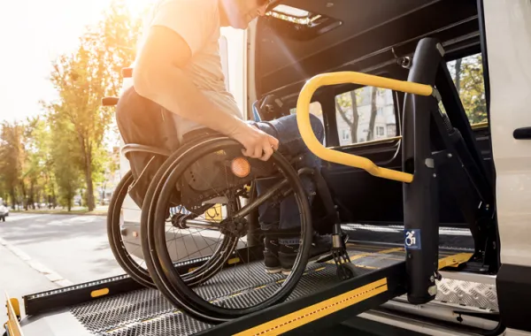 Foto de un chico en silla de ruedas saliendo de un vehículo adaptado