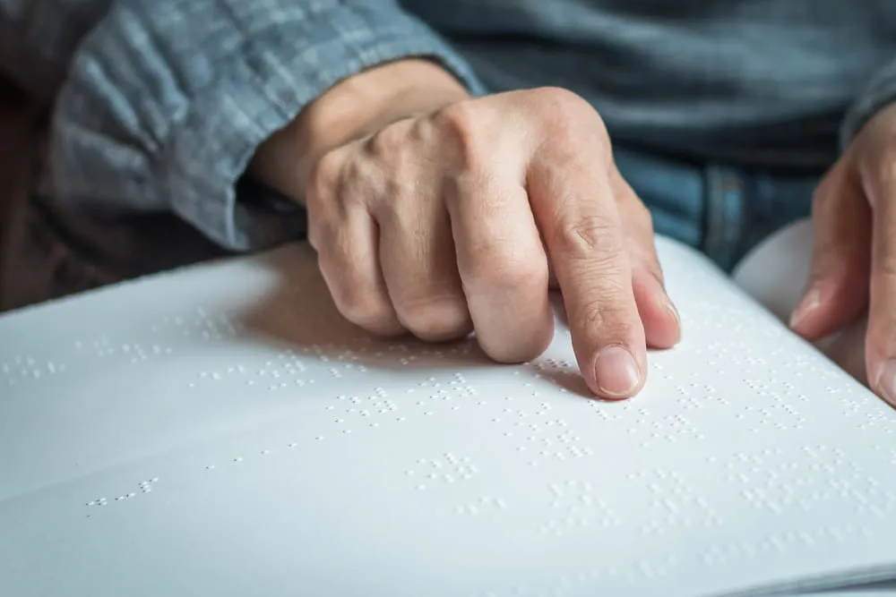 Foto mano leyendo documento  sistema braille.