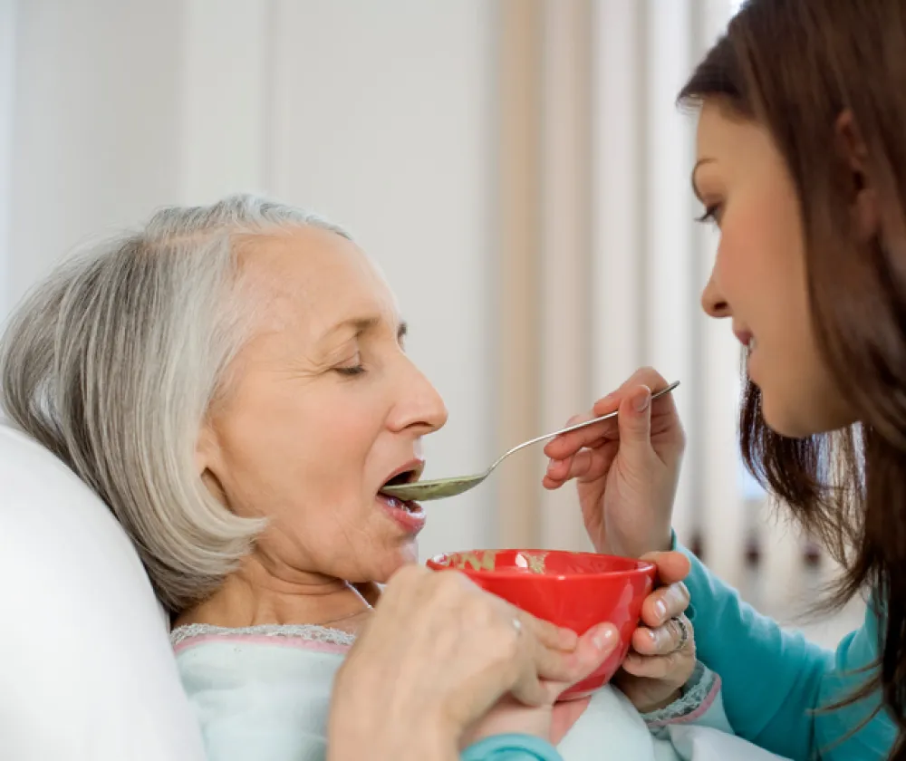 persona ayudando a comer a persona mayor