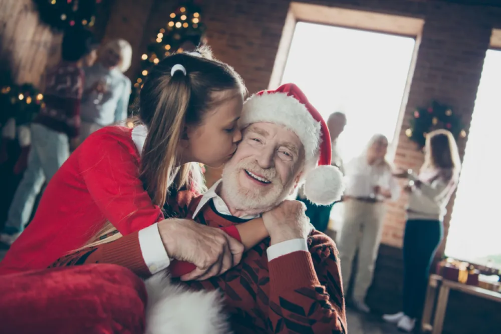 Foto de una nieta que abraza a su abuelo vestido de papa noel