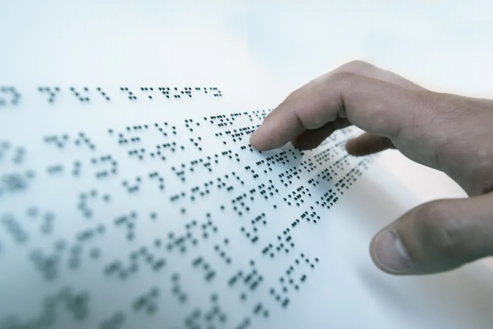 Foto de una mano leyendo un texto en braille
