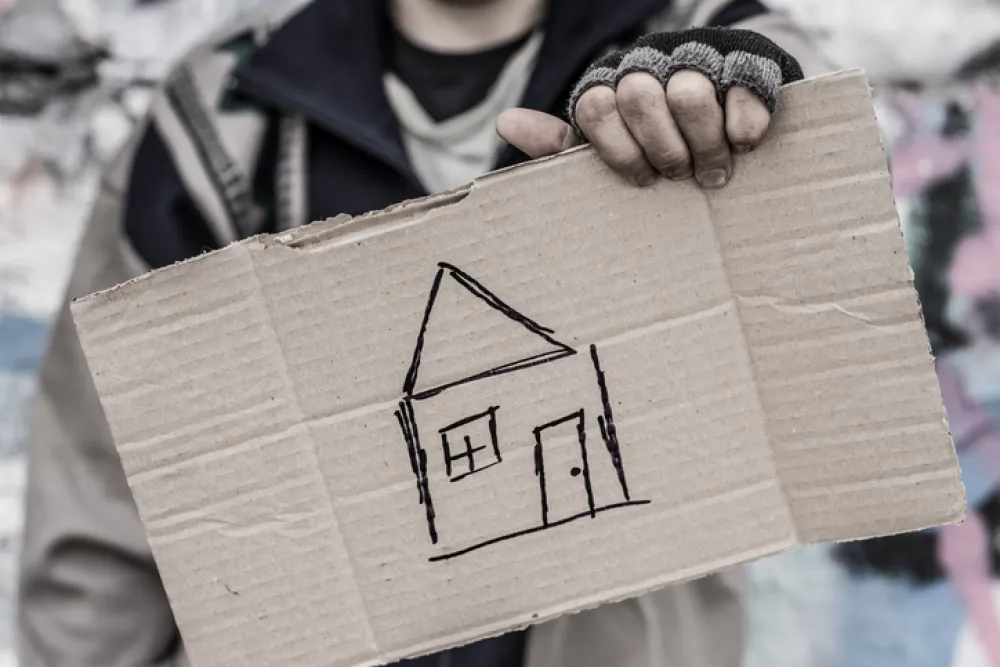 Foto de una  persona sosteniendo un cartón con una casa dibujada