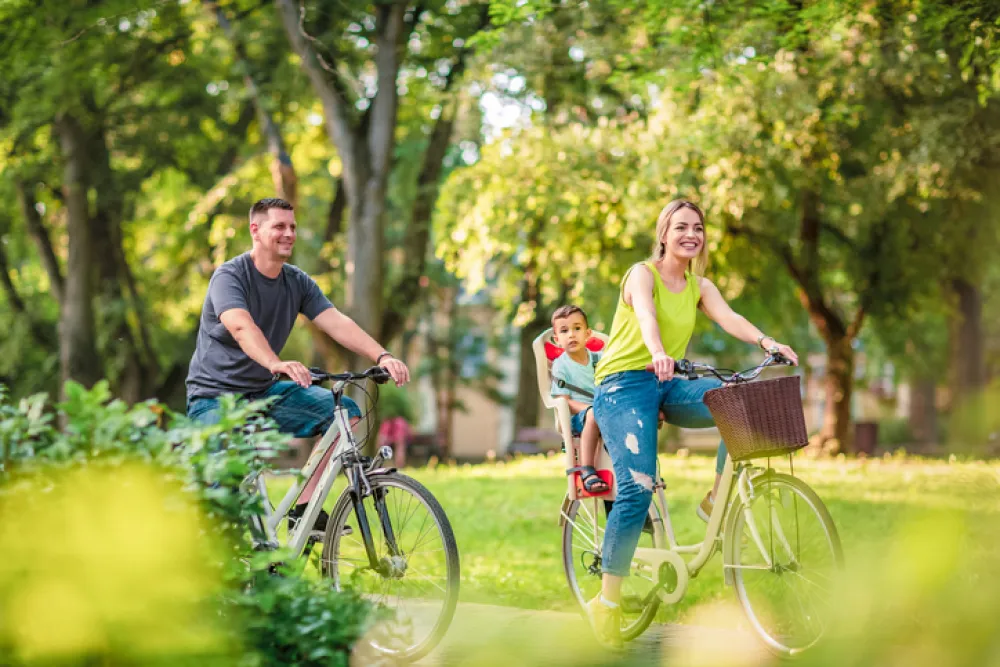 Foto de una pareja con un niño montando en bicicleta por un parque