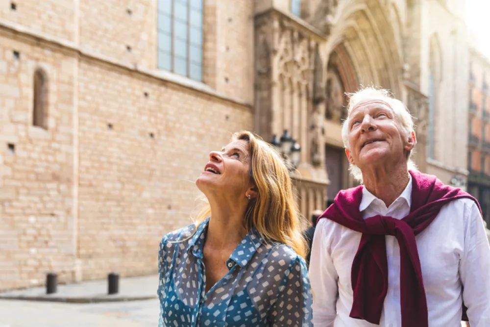Foto de dos personas mayores haciendo turismo por el casco antiguo de una ciudad