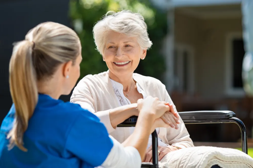Foto de una señora mayor sentada en una silla y conversando con una enfermera
