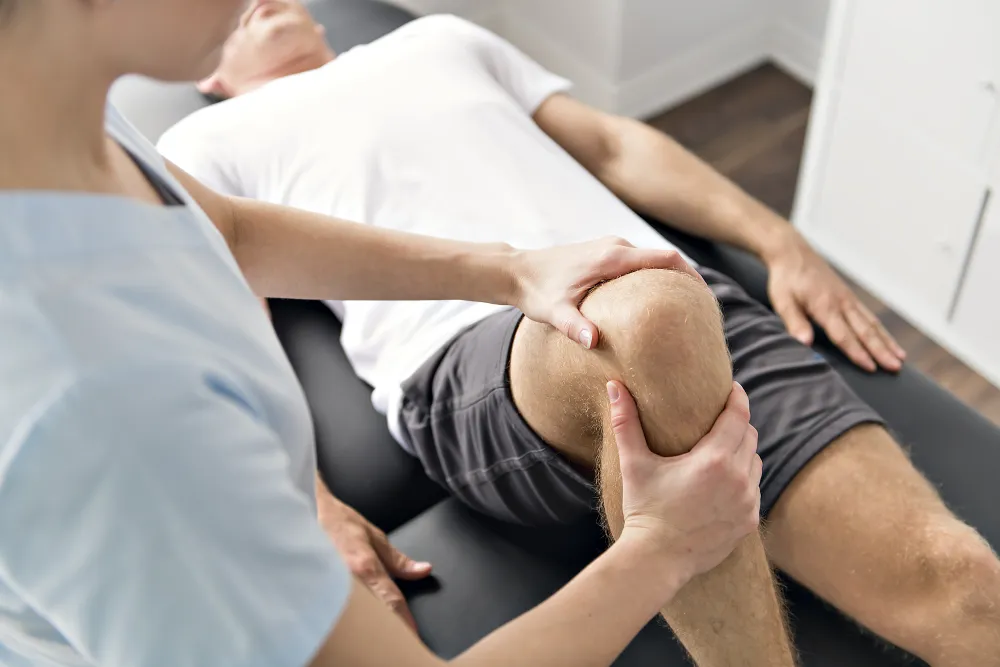 Foto de un fisioterapeuta dando un masaje en la rodilla de un corredor