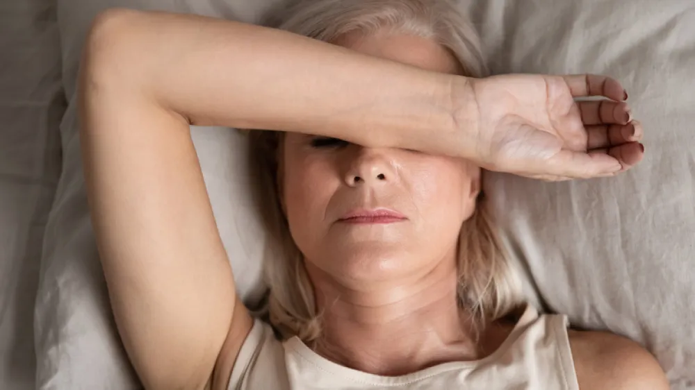 Foto de una mujer adulta tumbada que se tapa la cabeza con el brazo