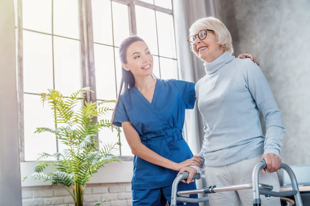 Foto de una mujer mayor con unas muletas acompañada de una enfermera joven