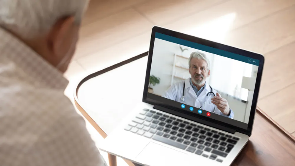 Foto de un señor mayor que está hablando por videoconferencia con su medico