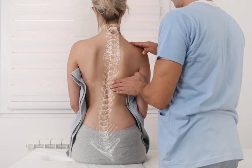 Foto de una persona en una camilla de espaldas atendido por un fisioterapeuta