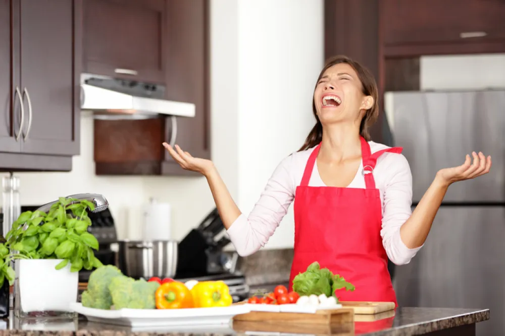 Foto de una mujer cocinando en una cocina y con gesto de sorpresa