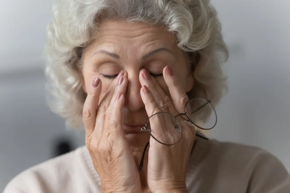 Foto de una mujer mayor tocándose los ojos con las manos en señal de cansanciio