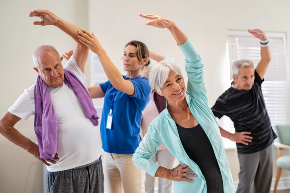Foto de varias personas adultas haciendo ejercicios acompañados por una fisioterapeuta
