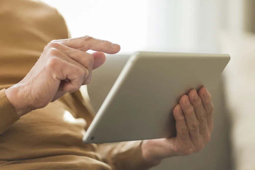 Foto de una manos de persona mayor que sostiene una tablet