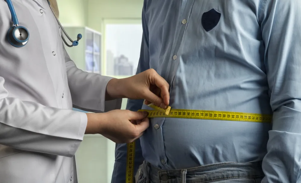 Foto del torso de un hombre que está siendo medido con una cinta métrica por un médico