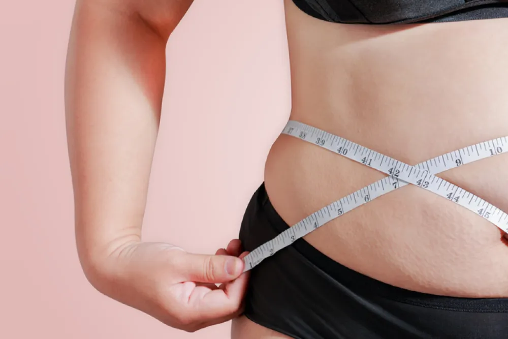 Foto de una persona que se mide la cintura con un metro para calcular la obesidad