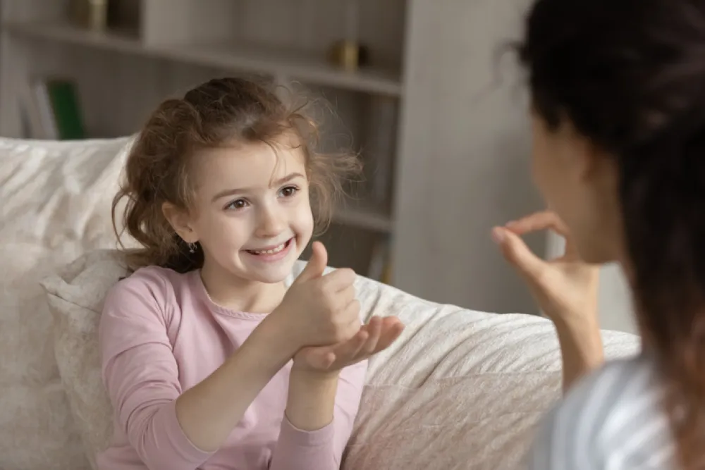 Foto de un niña hablando en lenguaje de signos con su madre