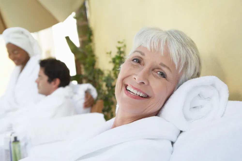Foto mujer con pelo blanco y sonriente tumbada ligeramente en una almohada toalla