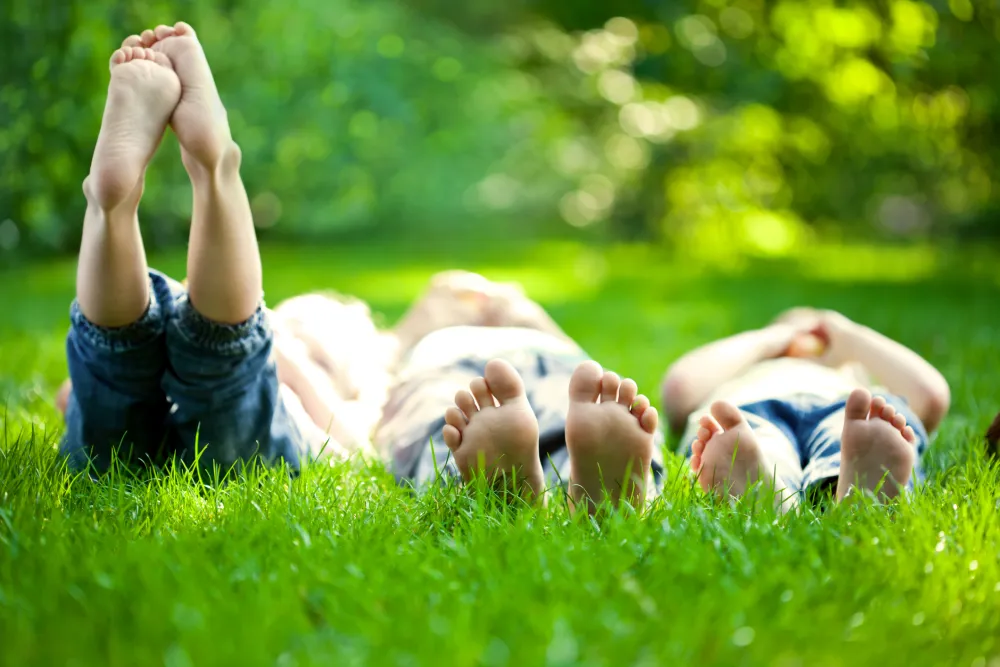 Foto con tres personas tumbadas en la hierba que muestran sus pies descalzos