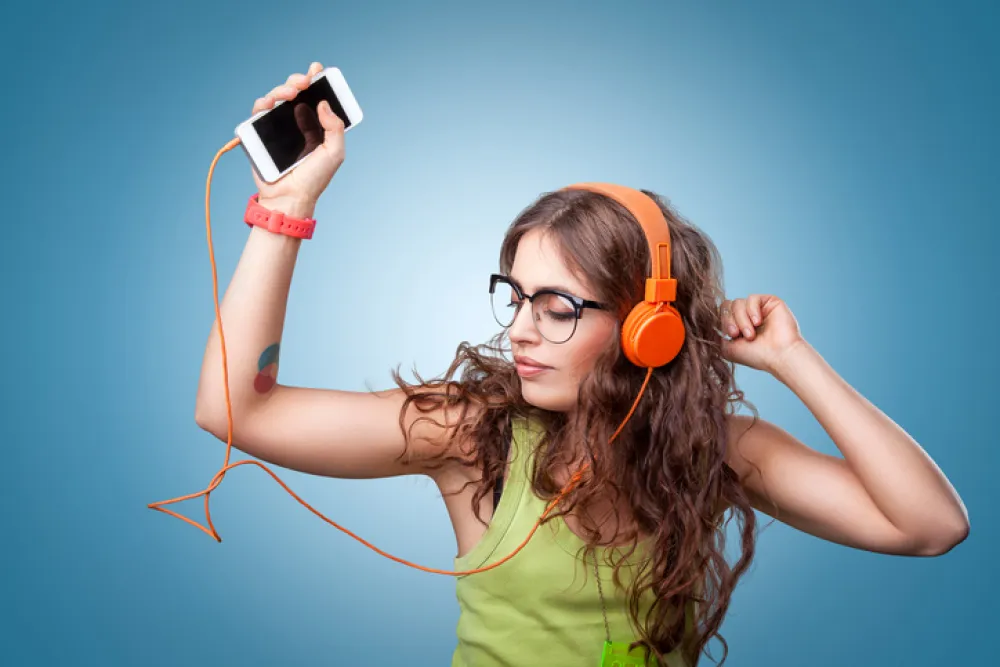 Foto de mujer joven escuchando música de un teléfono movil con los auriculares 