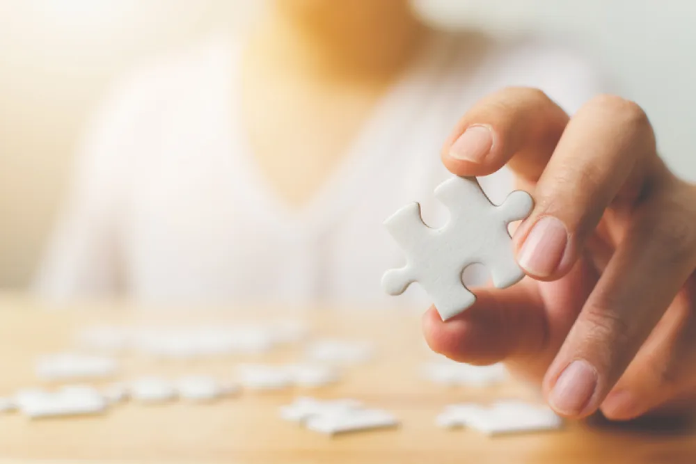 Foto con la mano de una persona mayor sosteniendo una pieza de un puzzle