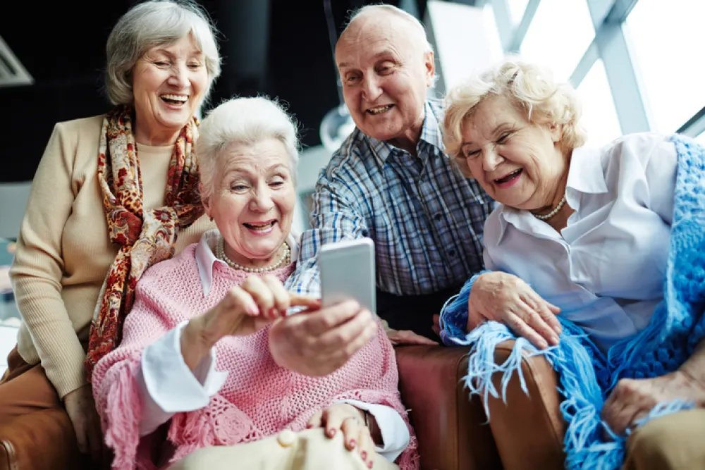 Foto de un grupo de personas mayores sonriendo mientras miran un movil