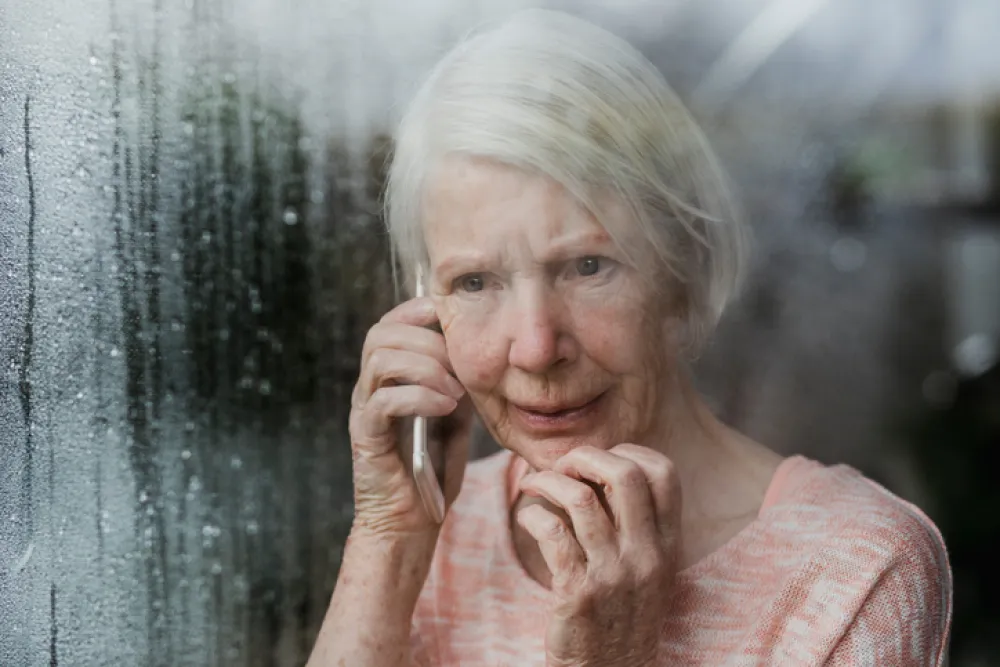 Foto de anciana con mirada triste y llamando por teléfono