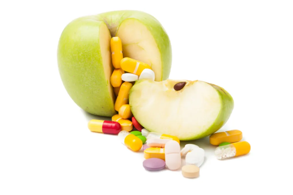 Foto de una manzana partida rodeadas de pastillas