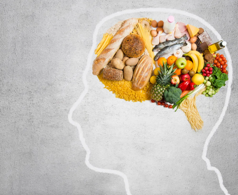Foto de un gráfico de una cabeza de lado con el cerebro lleno de verduras y frutas