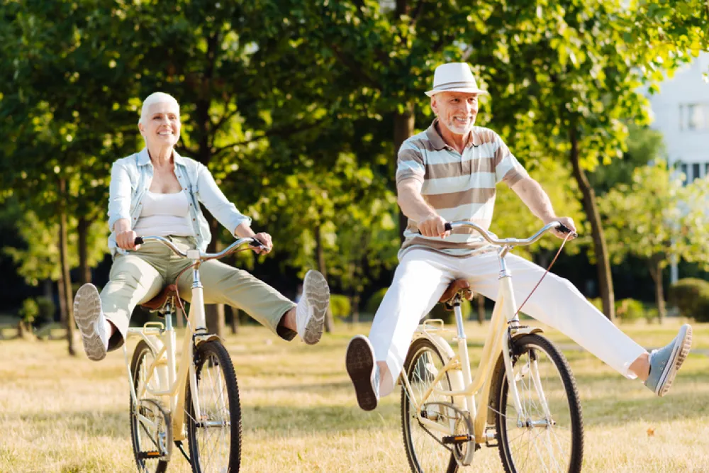 Foto de pareja de personas maduras montando en bici y sonriendo