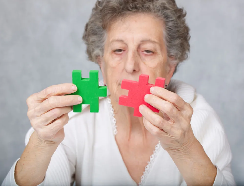 Foto de mujer mayor que mira unas piezas de puzzle sin poder encajarlas