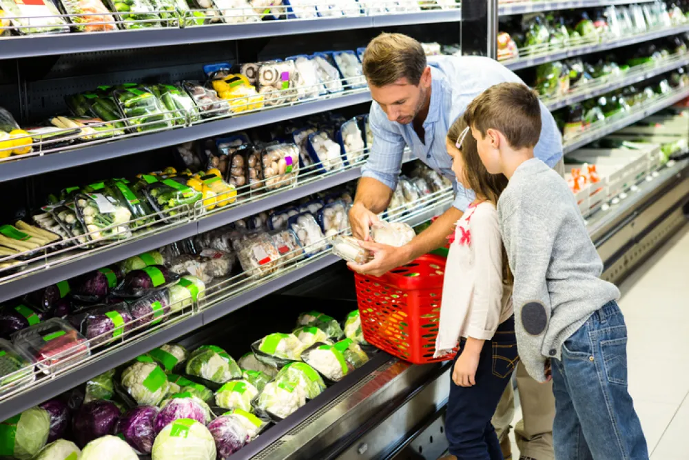 Foto de un padre comprando en el supermercado acompañado de sus hijos