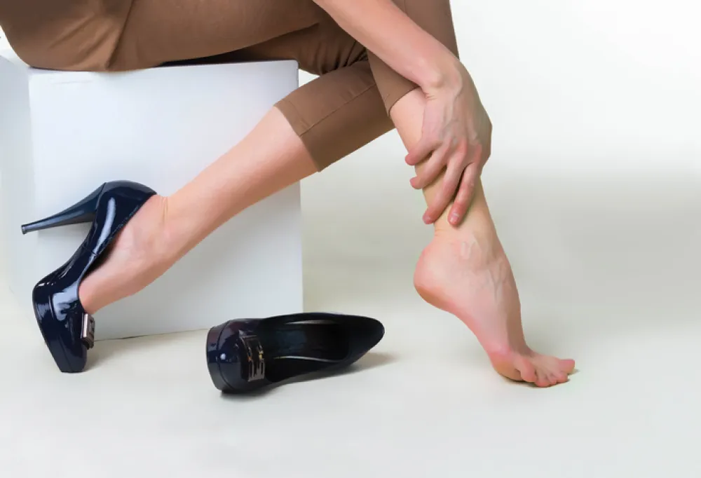 Foto de unos pies de mujer con el zapato quitado y que aprieta el piel con un mano