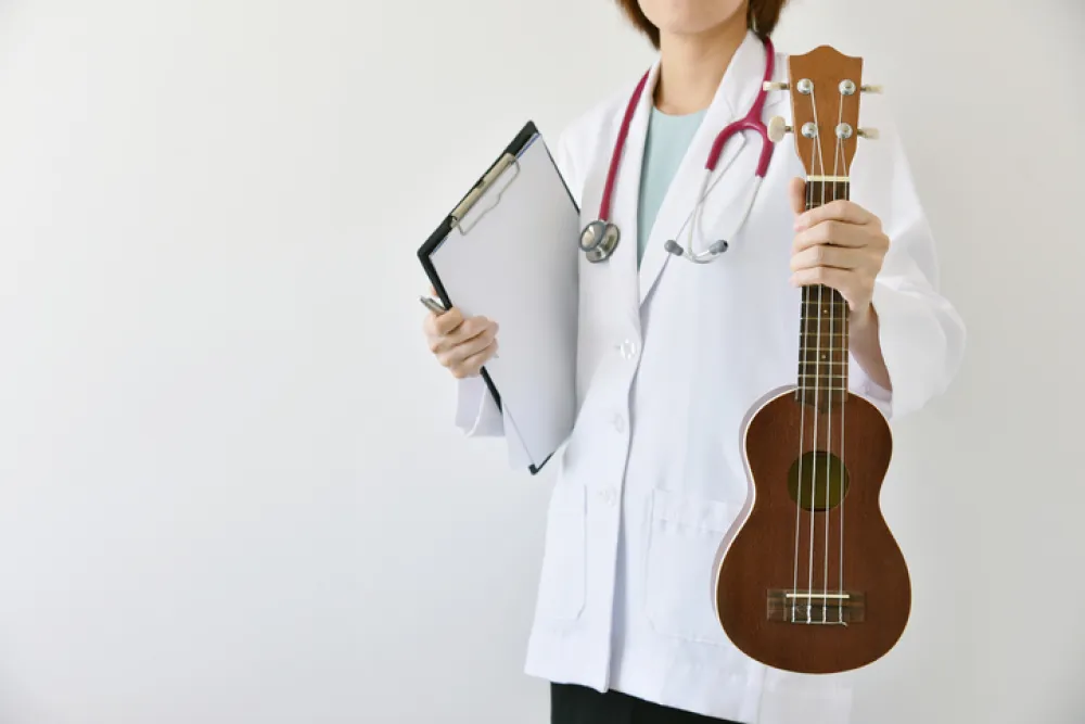 Foto de una doctora que sujeta con la mano una guitarra